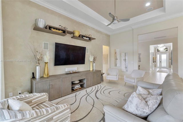 living area with light tile patterned floors, ornamental molding, a raised ceiling, and a ceiling fan