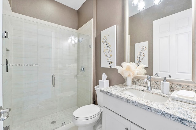 bathroom featuring toilet, a shower stall, and vanity