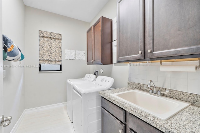 washroom featuring cabinet space, baseboards, a sink, and independent washer and dryer