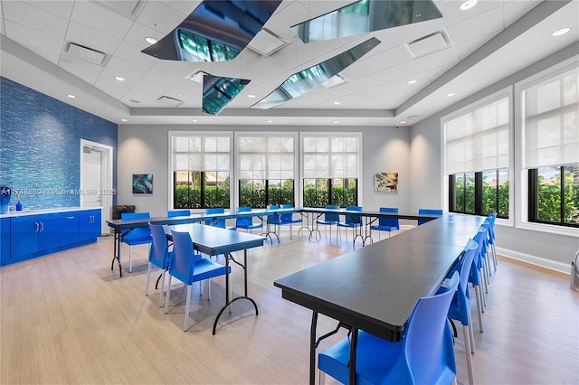 dining area featuring baseboards, an accent wall, light wood-style floors, and a healthy amount of sunlight