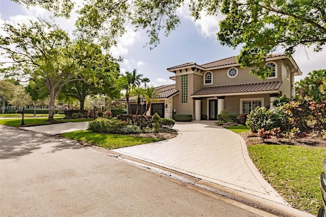 mediterranean / spanish-style home featuring decorative driveway, a tile roof, and stucco siding