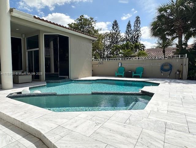 view of swimming pool with a patio area, fence, and a pool with connected hot tub