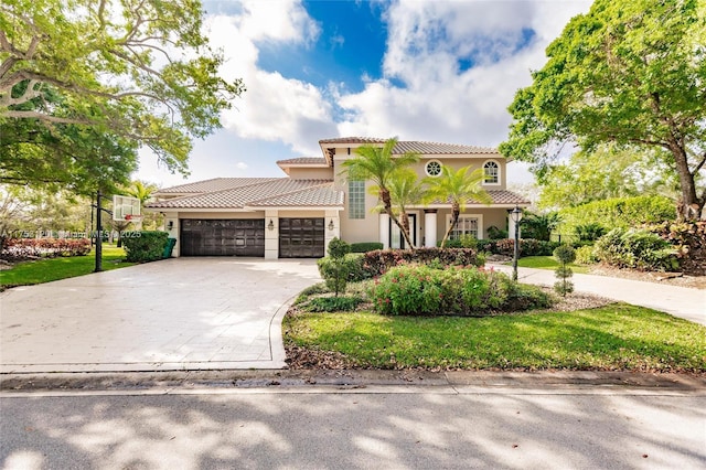 mediterranean / spanish home featuring concrete driveway, a tile roof, an attached garage, and stucco siding