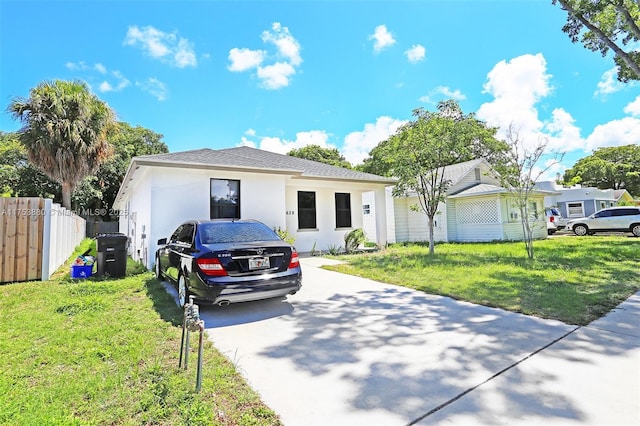 view of front of home with stucco siding, fence, and a front yard