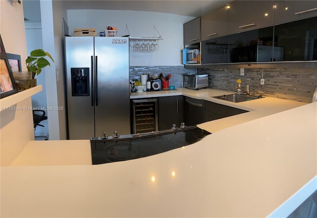 kitchen featuring wine cooler, a sink, light countertops, appliances with stainless steel finishes, and decorative backsplash