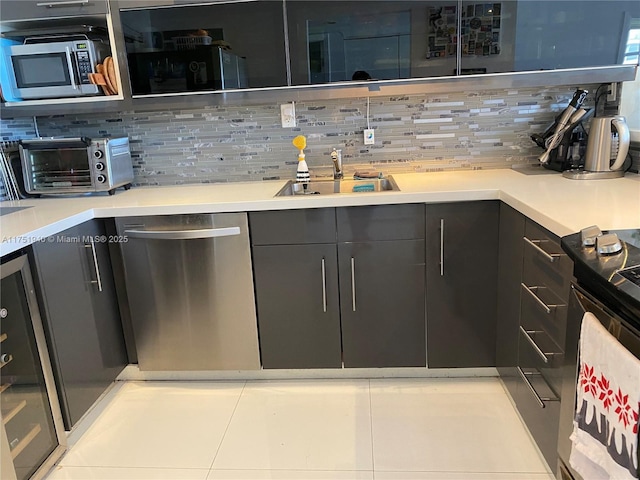 bar featuring a toaster, stainless steel appliances, tasteful backsplash, light tile patterned flooring, and a sink