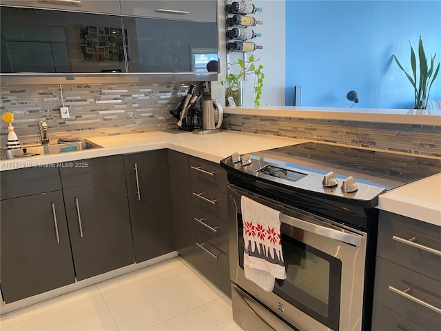 kitchen featuring light countertops, tasteful backsplash, a sink, and stainless steel electric stove