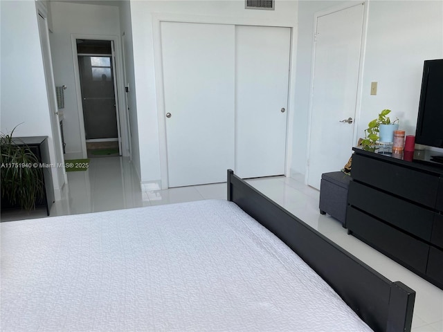 tiled bedroom with a closet and visible vents