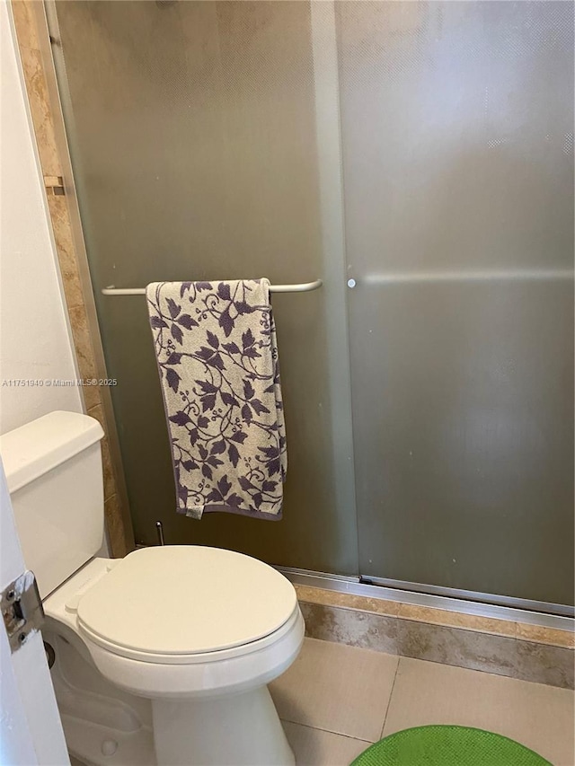 full bathroom with tile patterned flooring, a shower stall, and toilet