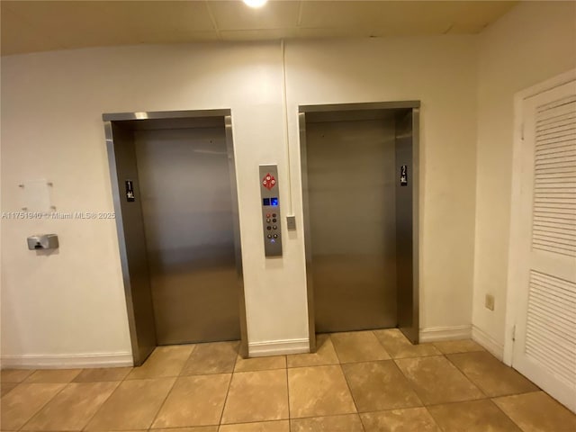 interior space with baseboards, light tile patterned flooring, and elevator