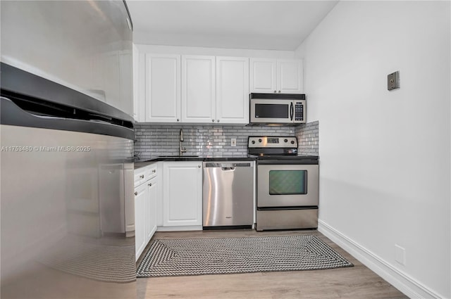 kitchen featuring appliances with stainless steel finishes, white cabinetry, a sink, and tasteful backsplash