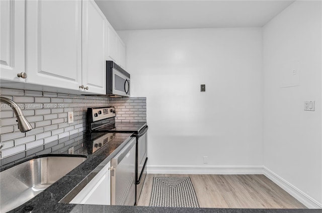 kitchen with tasteful backsplash, light wood-style flooring, appliances with stainless steel finishes, white cabinets, and a sink