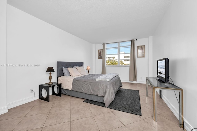 bedroom featuring a textured ceiling, baseboards, and light tile patterned floors