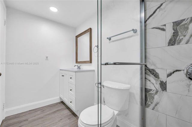 full bath with toilet, a shower stall, vanity, wood finished floors, and baseboards