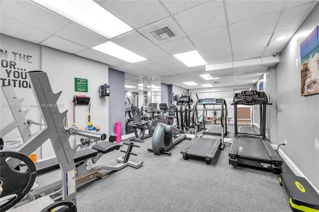 gym with a paneled ceiling, visible vents, and baseboards