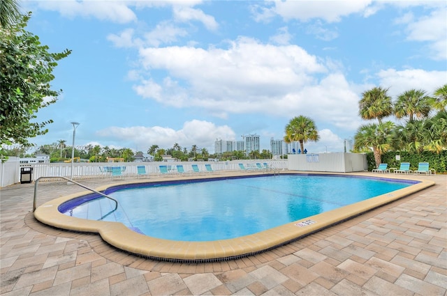 community pool with fence and a patio