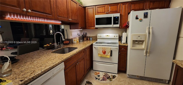 kitchen with white appliances, a sink, and light stone countertops