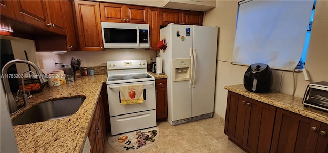 kitchen with light tile patterned floors, white appliances, a sink, and light stone counters