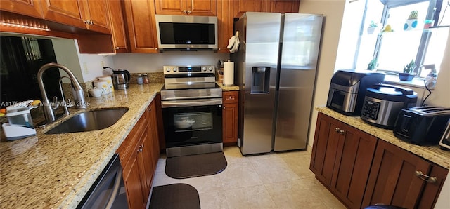 111 Gardens Dr Unit 203, Pompano Beach, FL 33069 - kitchen featuring appliances with stainless steel finishes, light stone counters, light tile patterned floors, and brown cabinetry