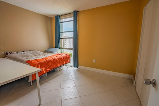 bedroom featuring light tile patterned floors, baseboards, and a textured ceiling