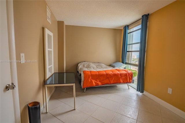 bedroom featuring a textured ceiling, a wall of windows, and baseboards