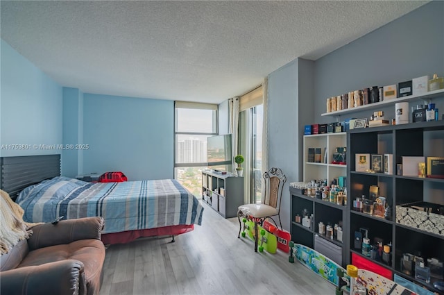 bedroom with a wall of windows, a textured ceiling, and wood finished floors