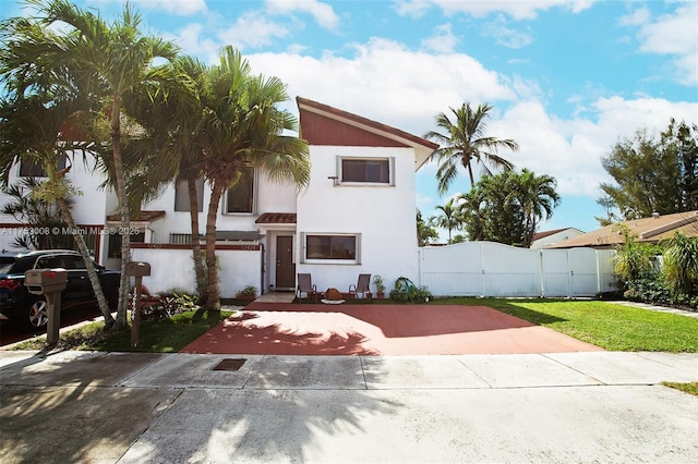 view of front of house with a front yard, a gate, fence, and stucco siding