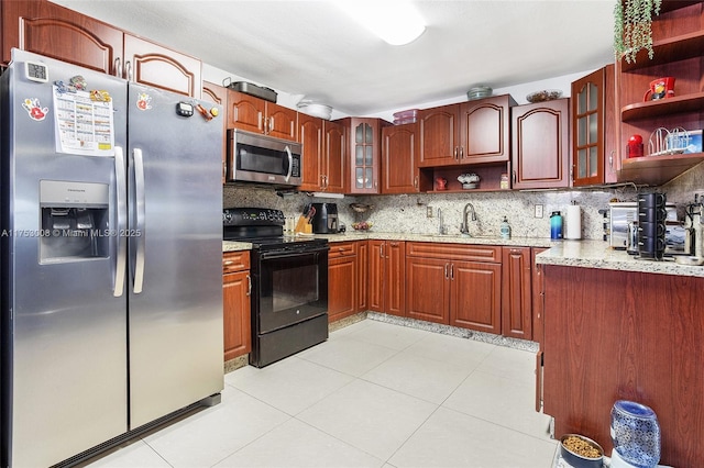 kitchen featuring tasteful backsplash, light stone countertops, stainless steel appliances, open shelves, and a sink