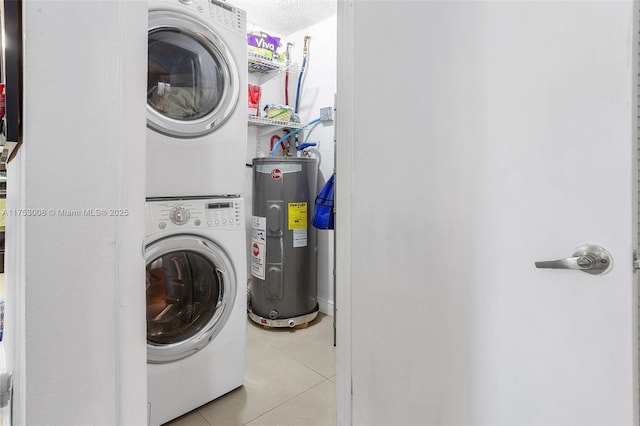 clothes washing area with light tile patterned floors, a textured ceiling, laundry area, stacked washer / dryer, and water heater