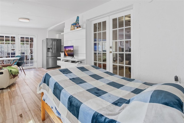 bedroom featuring light wood-style floors, access to outside, french doors, and stainless steel fridge with ice dispenser