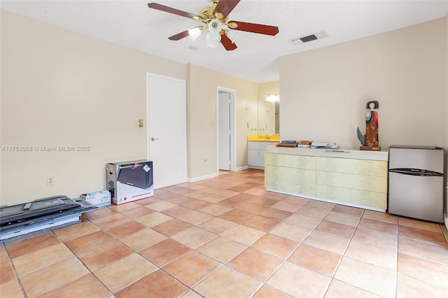 interior space with light tile patterned floors, baseboards, visible vents, and a ceiling fan