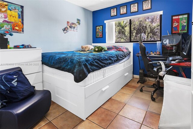 bedroom featuring light tile patterned floors, baseboards, and a textured ceiling