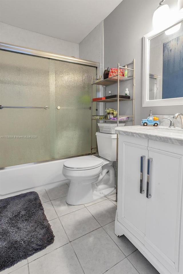 bathroom featuring enclosed tub / shower combo, vanity, toilet, and tile patterned floors