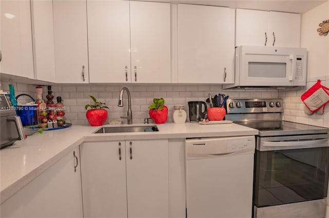 kitchen featuring white appliances, a sink, white cabinets, light countertops, and tasteful backsplash