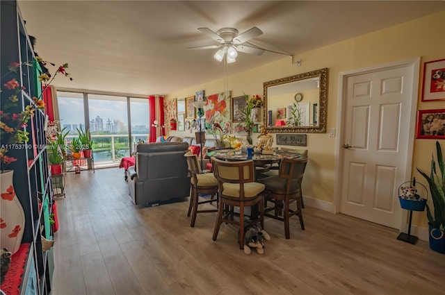 dining room with a view of city, baseboards, wood finished floors, and floor to ceiling windows