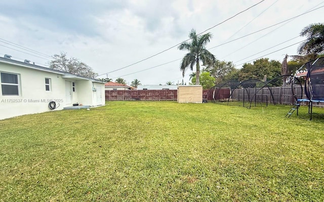 view of yard with a trampoline and a fenced backyard