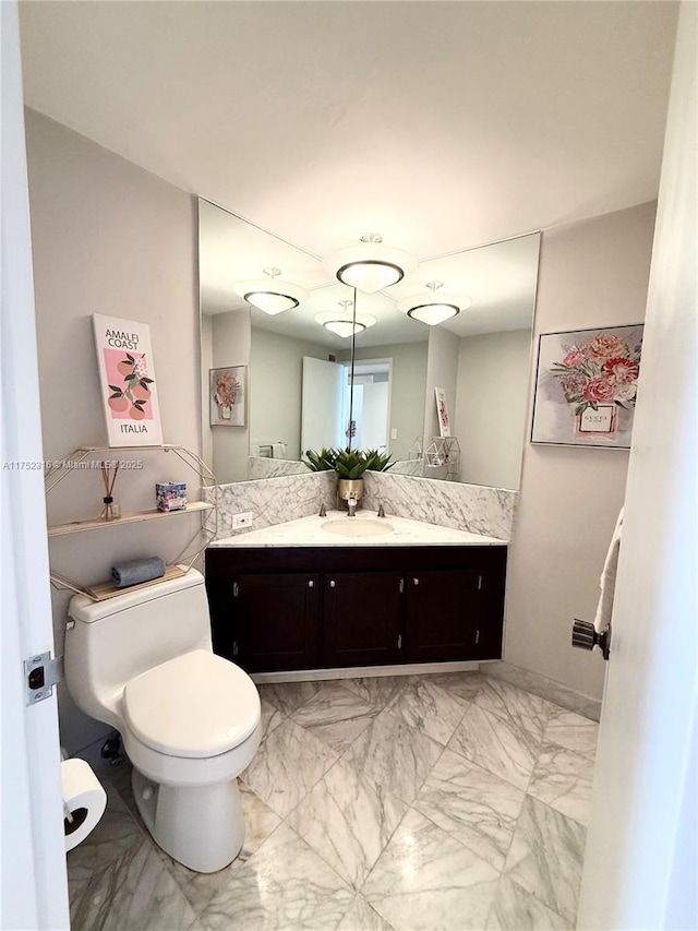 bathroom with marble finish floor, vanity, and toilet