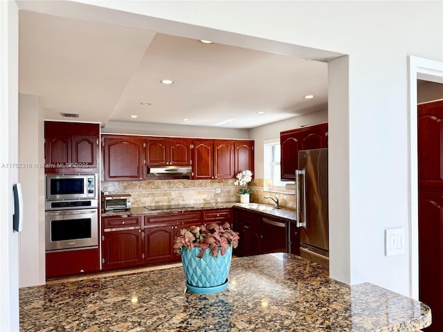 kitchen featuring stainless steel appliances, dark brown cabinets, decorative backsplash, and under cabinet range hood