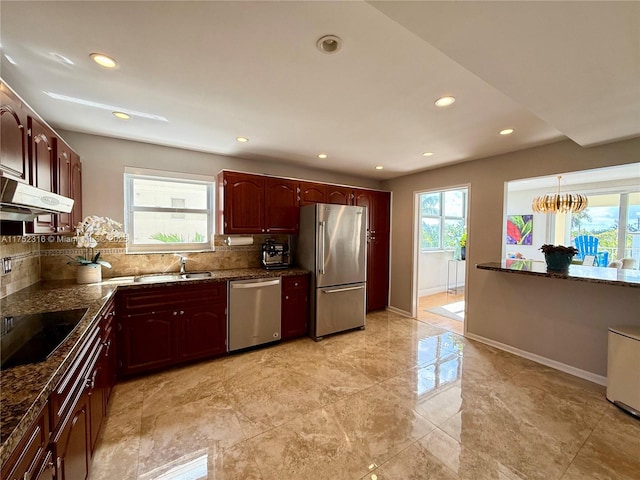 kitchen featuring appliances with stainless steel finishes, baseboards, dark stone countertops, and tasteful backsplash