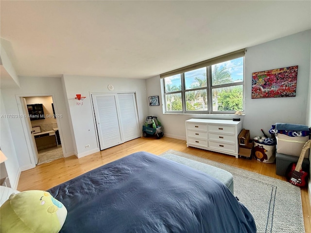 bedroom with baseboards, ensuite bathroom, and wood finished floors