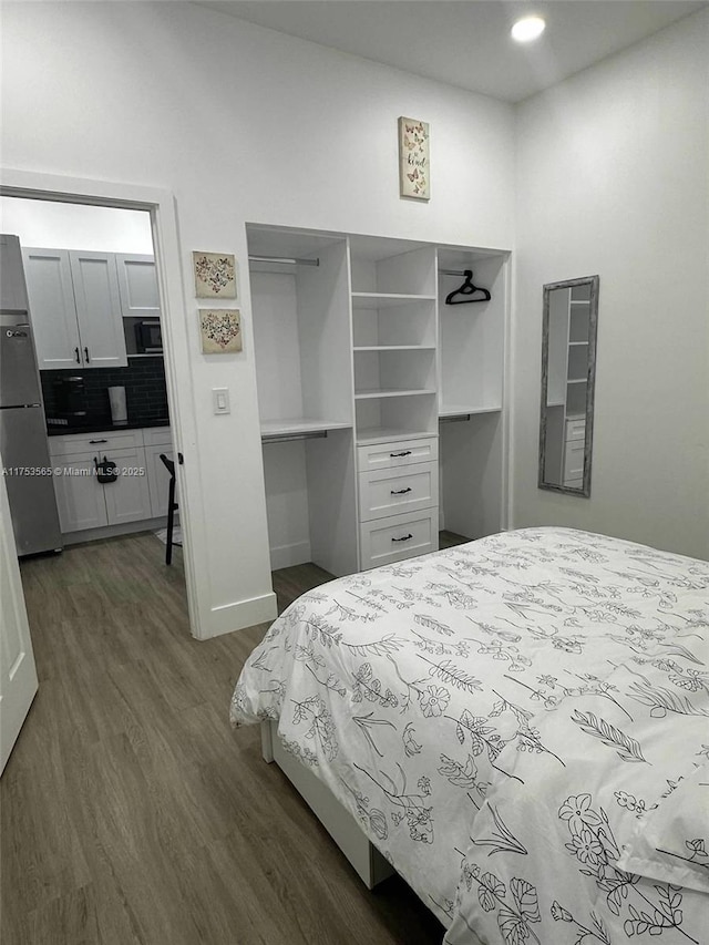 bedroom featuring baseboards, dark wood-style floors, fridge, a closet, and recessed lighting