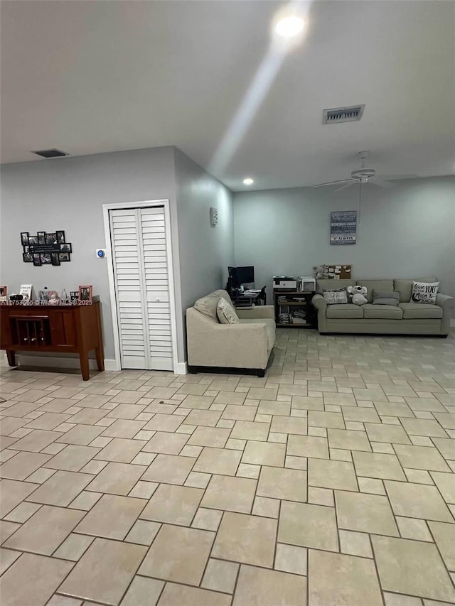 living area with light tile patterned floors, baseboards, visible vents, and a ceiling fan