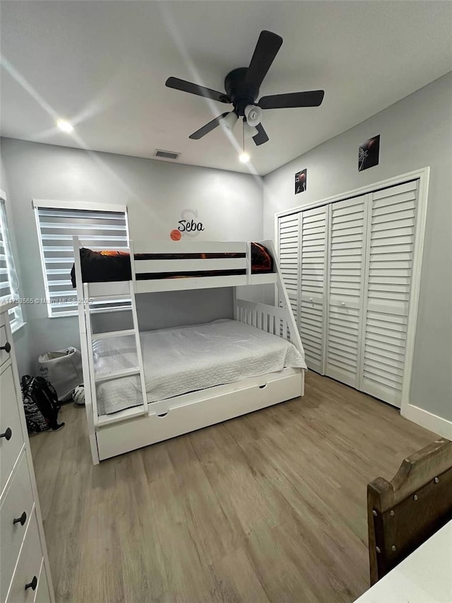 bedroom featuring a ceiling fan, visible vents, and wood finished floors