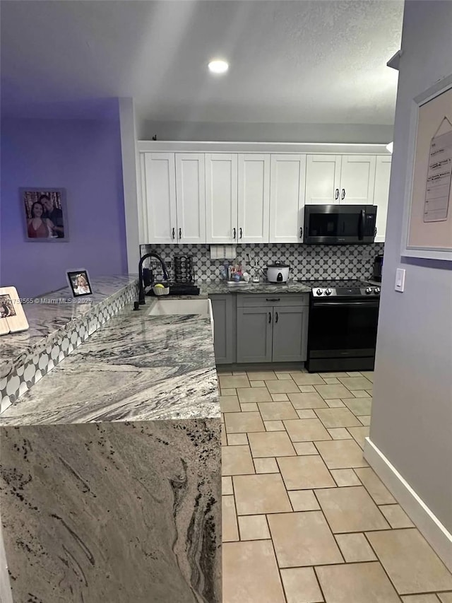 kitchen with black / electric stove, a sink, white cabinetry, and decorative backsplash