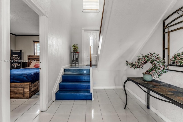 stairs with tile patterned floors, a textured wall, baseboards, and a textured ceiling