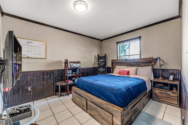 tiled bedroom with wainscoting, a textured ceiling, crown molding, and wood walls