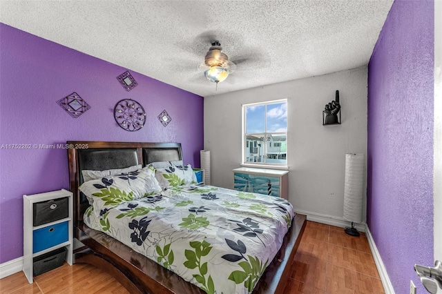 bedroom with a textured wall, a textured ceiling, baseboards, and wood finished floors