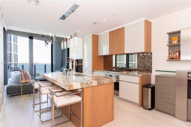 kitchen with white cabinets, modern cabinets, light stone counters, stainless steel appliances, and a sink