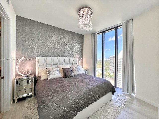 bedroom with expansive windows, wood finished floors, and baseboards