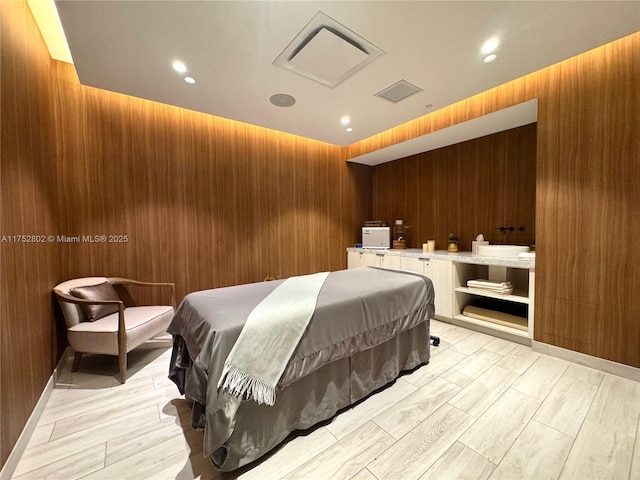 bedroom with attic access, wooden walls, visible vents, and wood finish floors